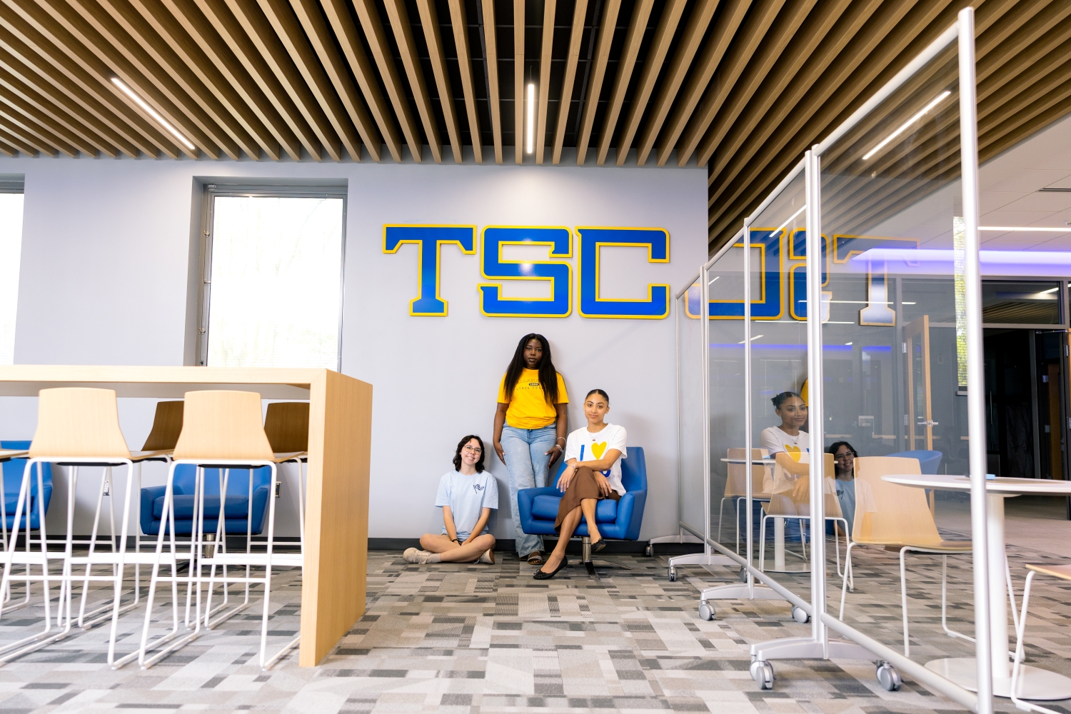 Three students posed under a blue TSC sign.