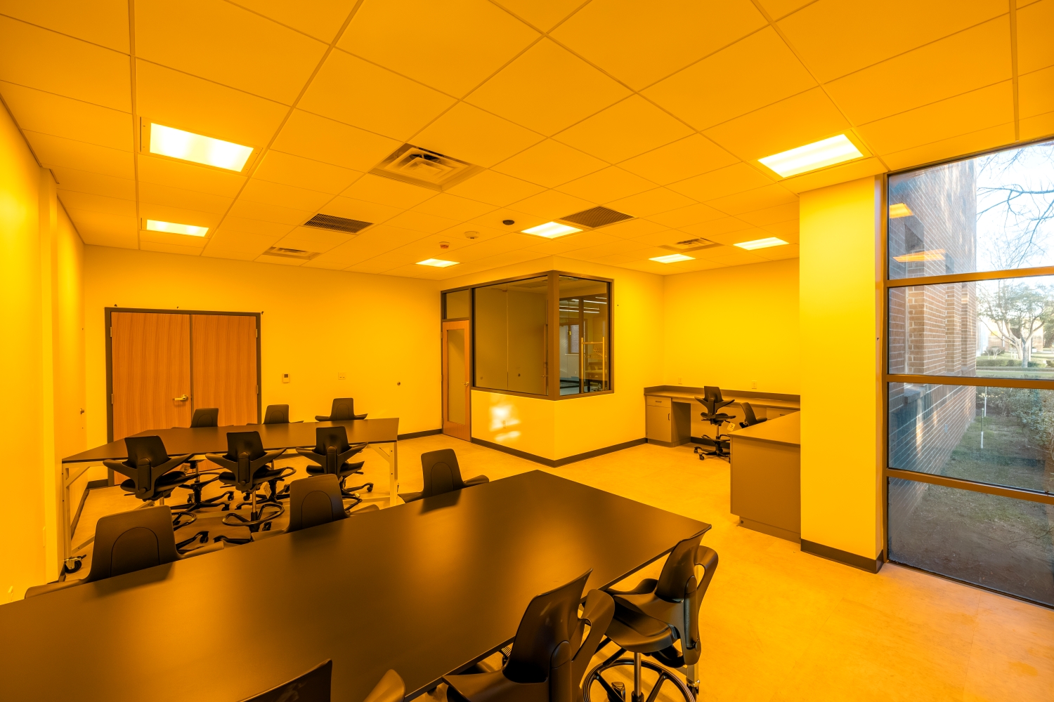 Yellow light room with empty tables and computer desks.