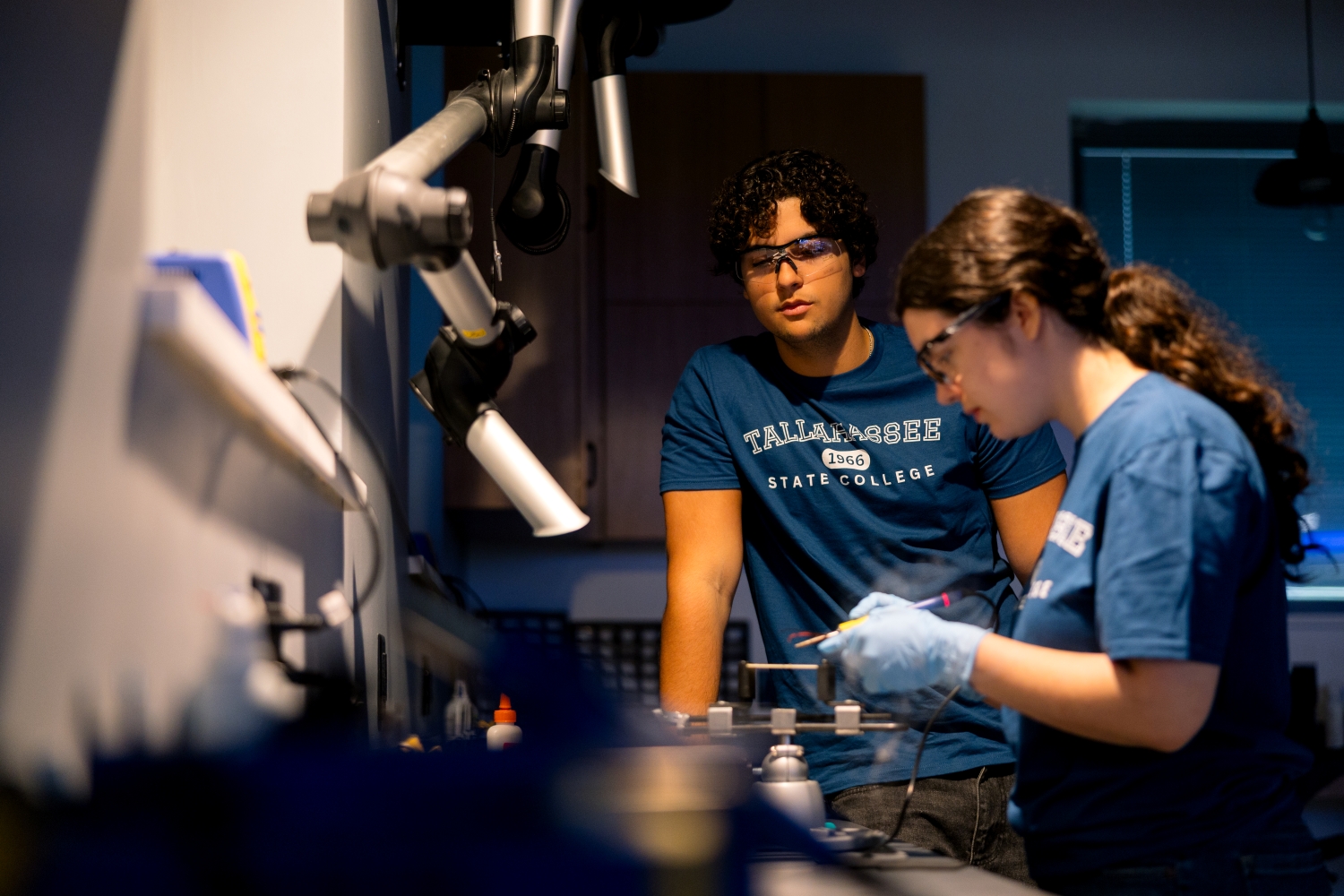 Two students using dark lab and engraving tools.